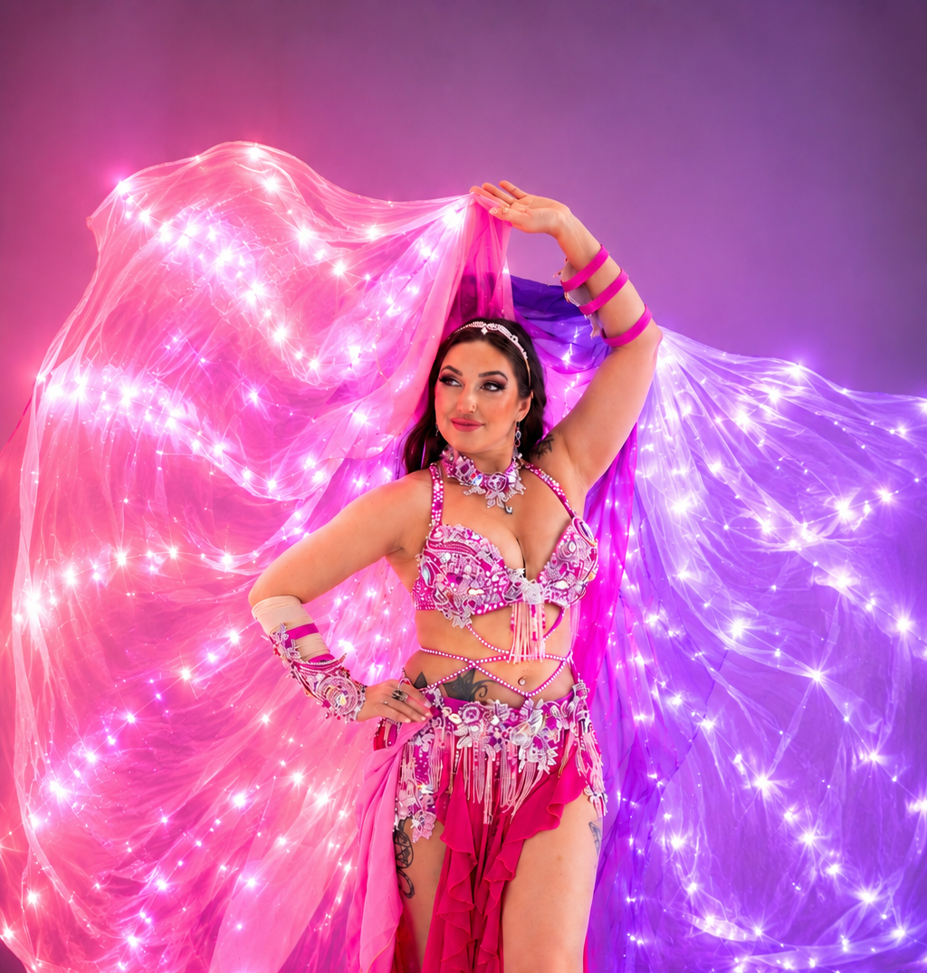 Dancer in a colorful costume with LED wings on a purple background